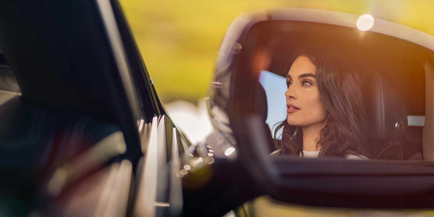 Bentley Hannover profile of dark haired woman's face in mirror of Bentley car in sunlight