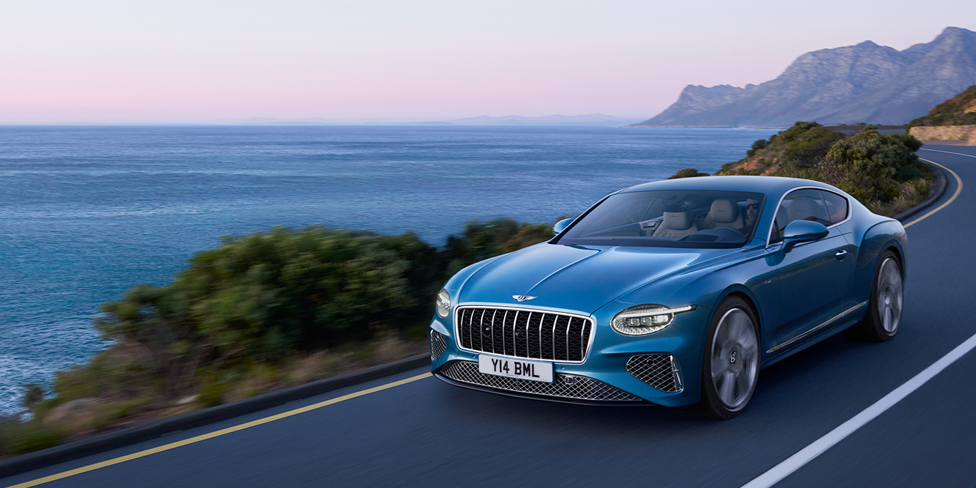 Bentley Hannover New Bentley Continental GT Azure coupe in Light Windsor blue paint with 22 inch Azure wheels and chrome grill, driving dynamically by the sea