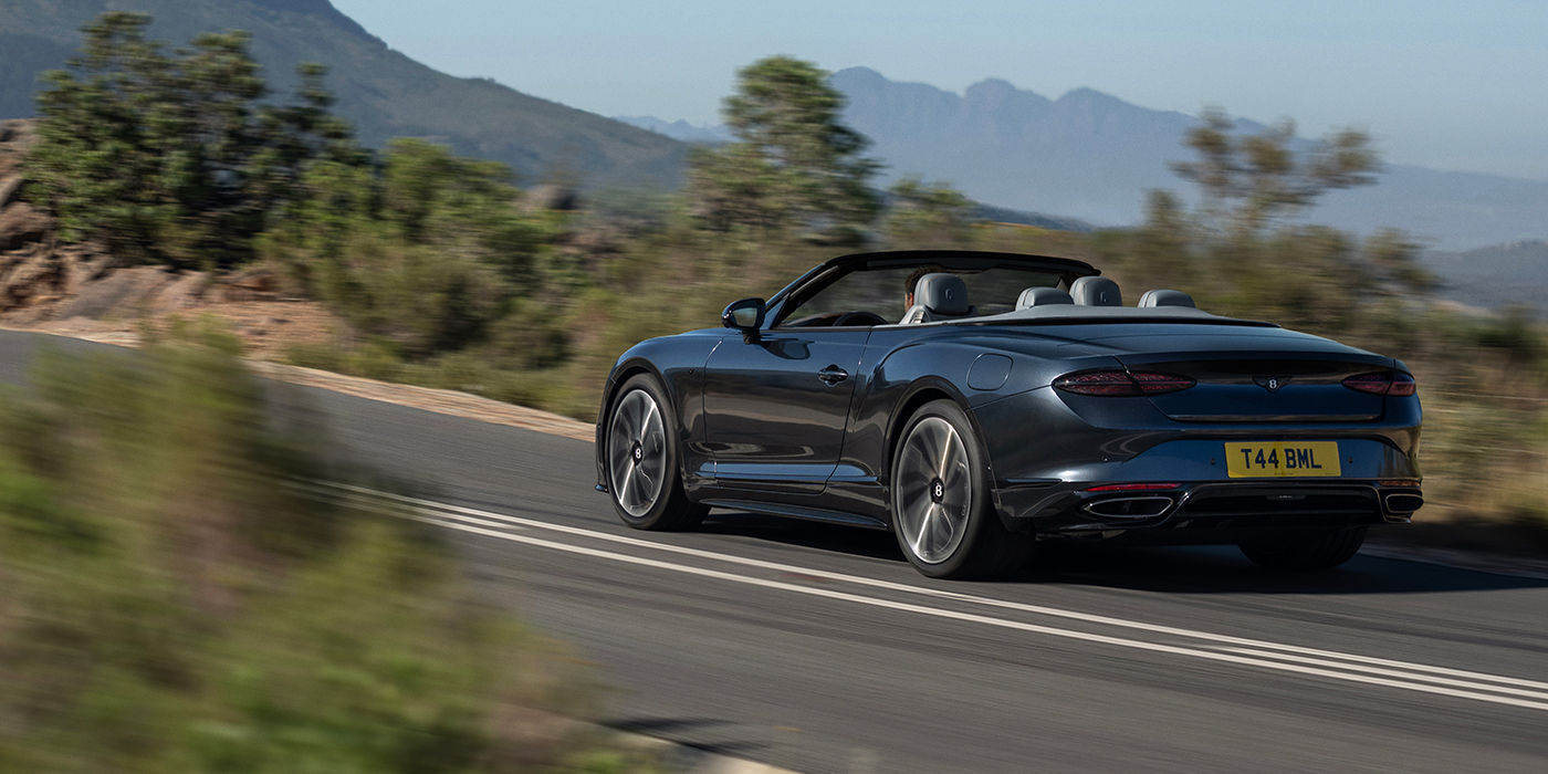 Bentley Hannover Bentley Continental GTC S convertible in Thunder blue paint rear 3/4 driving on mountain road