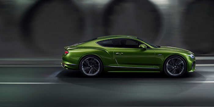 Bentley Hannover Bentley Continental GT coupe in Tourmaline Green paint driving in profile on a dark road