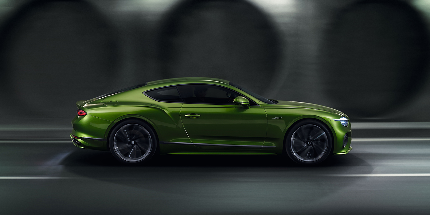 Bentley Hannover Bentley Continental GT coupe in Tourmaline Green paint driving in profile on a dark road